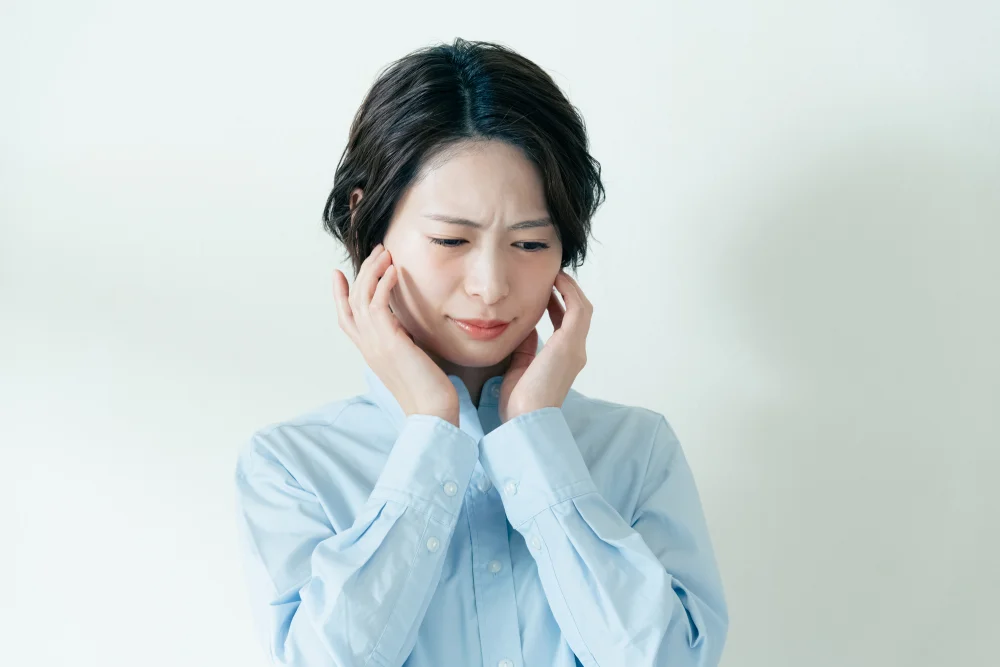 顎の痛みで頬を押さえる女性